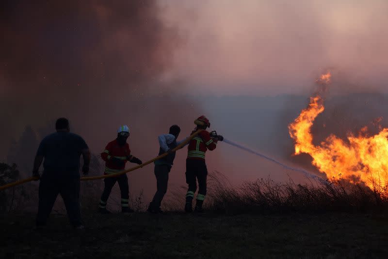 A firefighter and locals try to extinguish a wildfire in Cascais