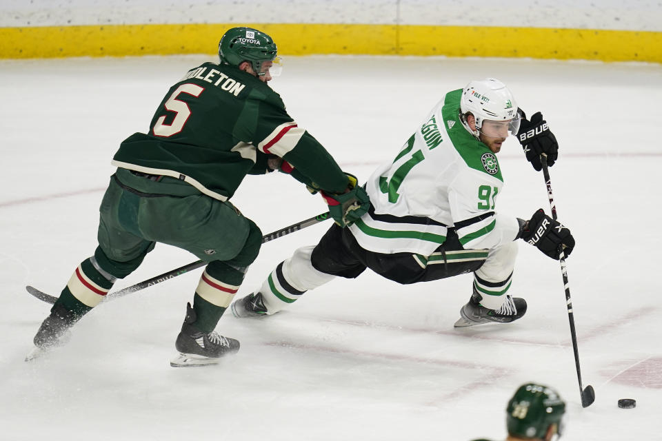 Dallas Stars center Tyler Seguin, right, skates with the puck against Minnesota Wild defenseman Jake Middleton (5) during the first period of an NHL hockey game Friday, Feb. 17, 2023, in St. Paul, Minn. (AP Photo/Abbie Parr)