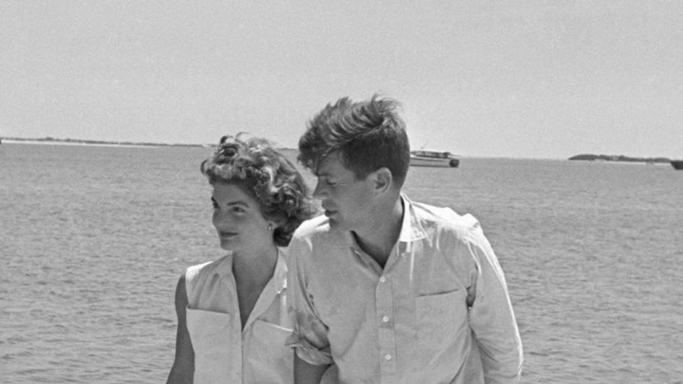 Senator John F. Kennedy with 24-year-old fiancee Jackie Bouvier at the family compund. The two are in khakis and walking on the beach.