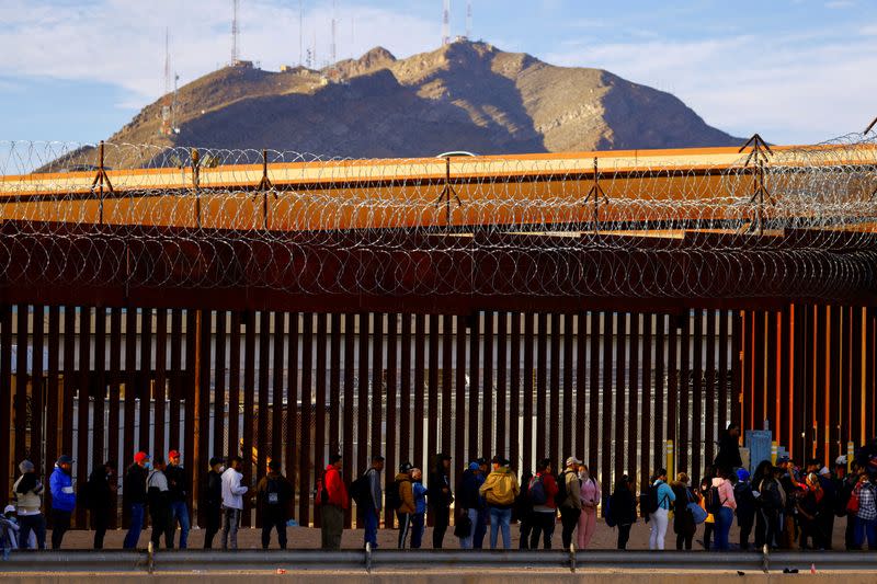 FILE PHOTO: Migrants queue near the border fence, after crossing the Rio Bravo river, to request asylum in El Paso