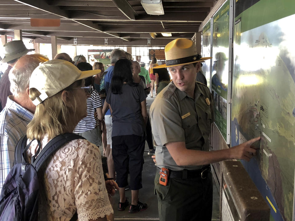 In this Saturday, Sept. 22,2018, photo released by the National Park Service shows tourists get directions on the first day Hawaii Volcanoes National Park is reopened after volcanic activity forced the park to close for more than four months in Hawaii. (Janice Wei/National Park Service via AP)