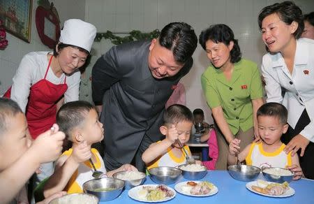 FILE PHOTO: North Korean leader Kim Jong Un smiles as children eat during his visit to the Pyongyang Orphanage on International Children's Day in this undated photo released by North Korea's Korean Central News Agency (KCNA) in Pyongyang June 2, 2014. To match Insight NORTHKOREA-FOOD/ KCNA / via REUTERS/File Photo