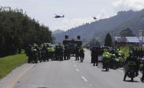 Police stand on a highway during anti-government protests and roadblocks in Gachancipa, Colombia, Friday, May 7, 2021. Protests that began last week over a tax reform proposal continue despite President Ivan Duque's withdrawal of the tax plan on Sunday, May 2. (AP Photo/Ivan Valencia)