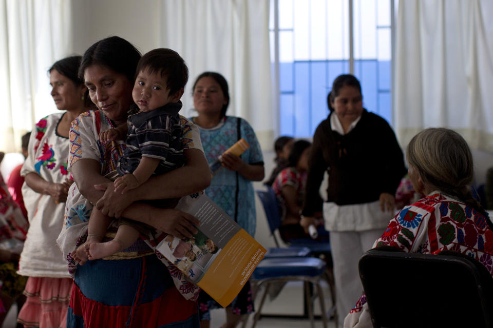 In this Tuesday, Feb. 11, 2014 photo, a Mixteco indigenous woman holds her son while waiting at a health clinic in Cochoapa El Grande, Mexico. The head of Mexico’s anti-poverty program drew criticism Monday, May 5, 2014, after she warned Indian mothers that government aid programs would only help support their first three children. (AP Photo/Dario Lopez-Mills)