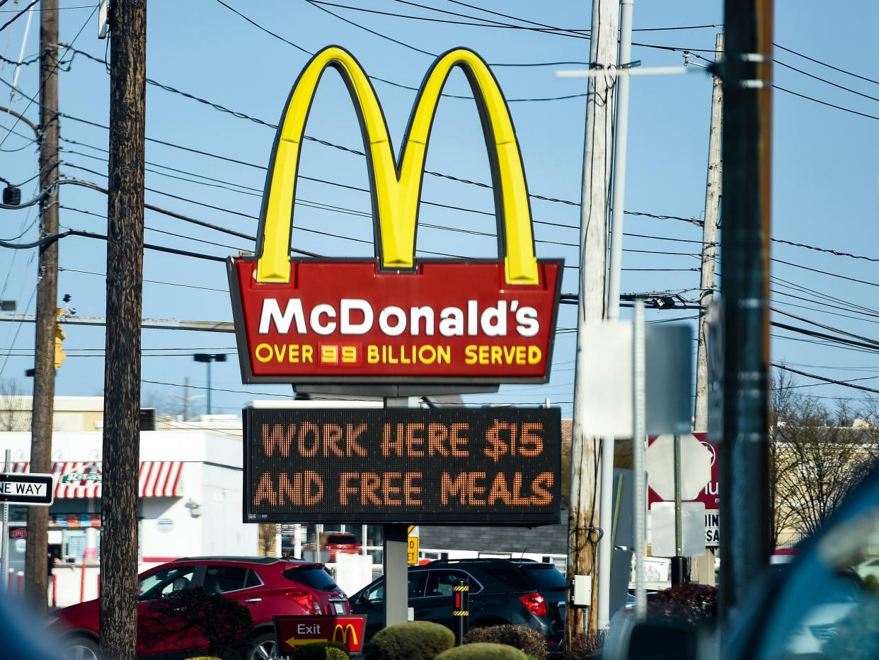 A McDonald's logo with a billboard below that says "work here $15 and free meals"