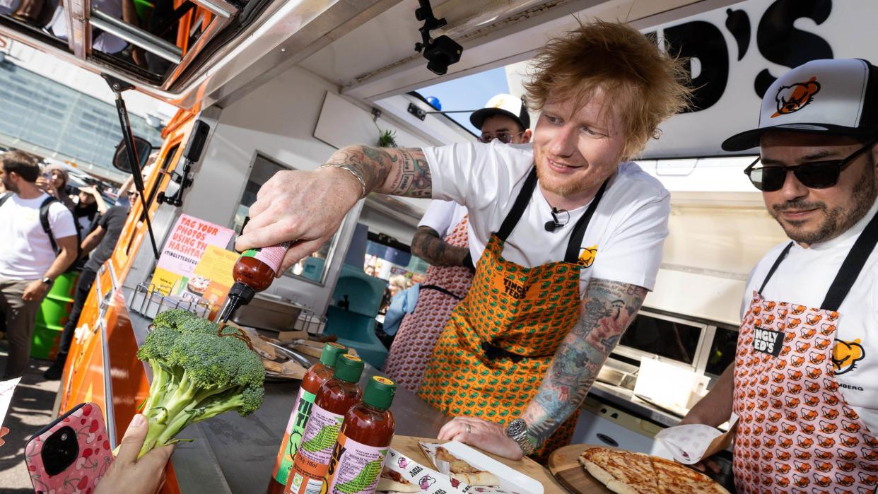 Ed Sheeran signs a head of broccoli in hot sauce outside a Sainsbury's supermarket in London Colney to promote his Tingly Ted's hot sauce brand