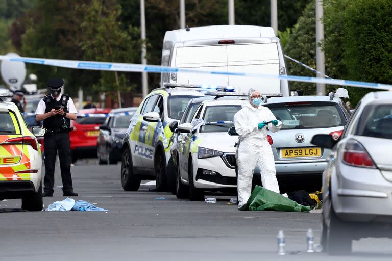 Agentes de policía y personal forense permanecen detrás de un cordón en Hart Street en Southport, noroeste de Inglaterra, el 29 de julio de 2024, tras un ataque con cuchillo.