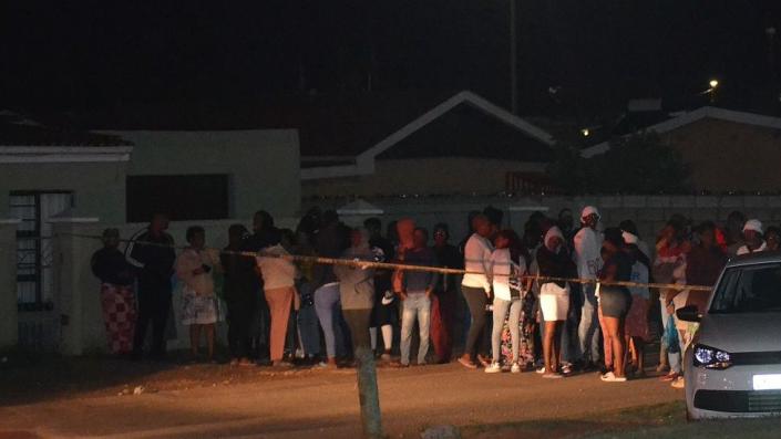 Bystanders wait behind a police tape marking the scene of a mass shooting