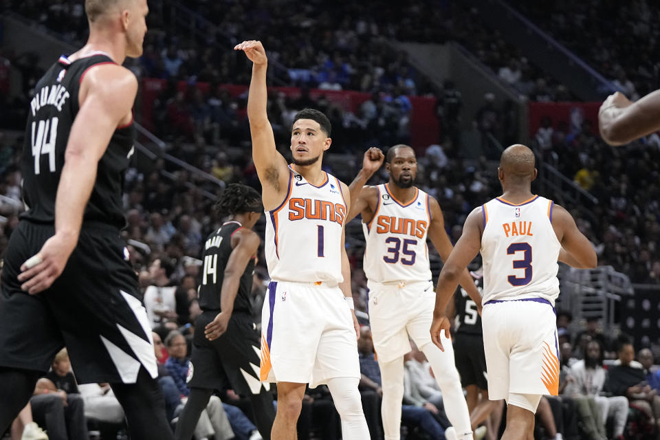 Phoenix Suns guard Devin Booker (1) holds his pose after hitting a 3-point shot as forward Kevin Durant (35) and guard Chris Paul (3) congratulate each other while Los Angeles Clippers center Mason Plumlee walks away during the second half in Game 4 of a first-round NBA basketball playoff series Saturday, April 22, 2023, in Los Angeles. (AP Photo/Mark J. Terrill)