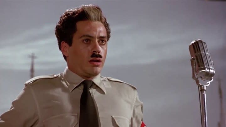 Robert Downey Jr. as Charlie Chaplin in Chaplin wearing a uniform with a small moustache and stunned look.