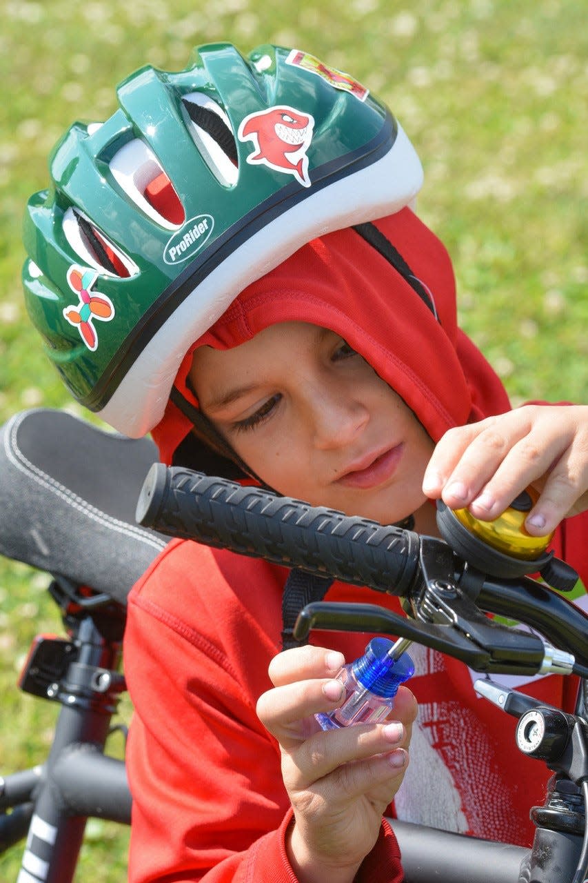 Eight-year-old Miles Moyer of Oak Harbor adjusts his new bell for his new bike on Bike Safety Day.