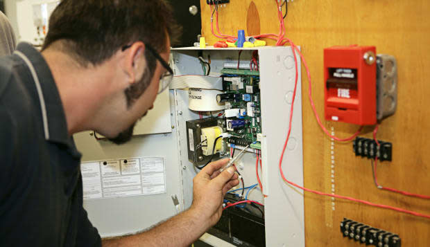 B7817M A student electrician wiring a fire alarm system at his technical college