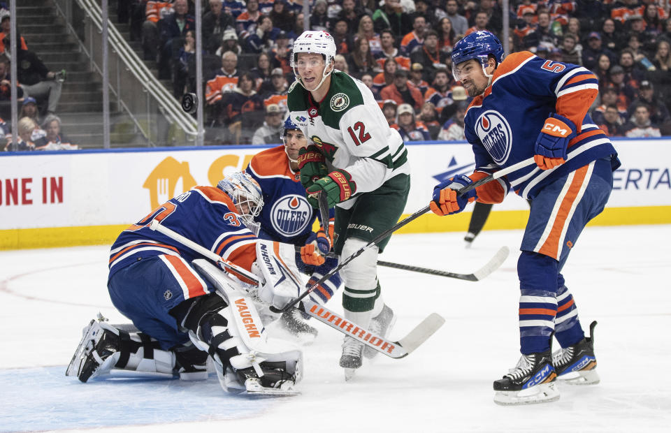 Minnesota Wild's Matt Boldy (12) looks for the rebound from Edmonton Oilers goalie Calvin Pickard (30) as Cody Ceci (5) defends during the first period of an NHL hockey game Friday, Feb. 23, 2024, in Edmonton, Alberta. (Jason Franson/The Canadian Press via AP)