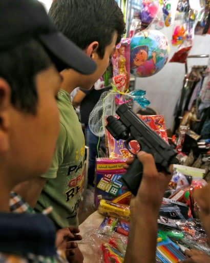 A boy holds a toy gun during a visit on May 13, 2018 to a government-sponsored market in Douma, on the outskirts of the capital Damascus