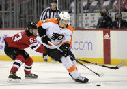 Philadelphia Flyers defenseman Travis Sanheim (6) skates with the puck as he is checked by New Jersey Devils left wing Jesper Bratt (63) during the first period of an NHL hockey game Sunday, Nov. 28, 2021, in Newark, N.J. (AP Photo/Bill Kostroun)