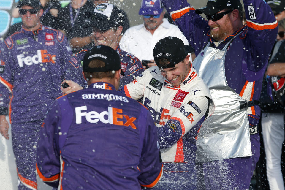 Denny Hamlin, center, gets sprayed with champagne by pit crew members in Victory Lane after he won the NASCAR Cup Series auto race Sunday, Nov. 10, 2019, in Avondale, Ariz. (AP Photo/Ralph Freso)