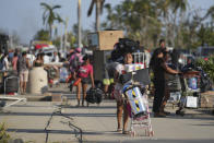 People walk away with items taken from stores after Hurricane Otis ripped through Acapulco, Mexico, Thursday, Oct. 26, 2023. Many residents were taking basic items from stores to survive. Others left with pricier goods, in widespread rampages through the area's stores. (AP Photo/Felix Marquez)