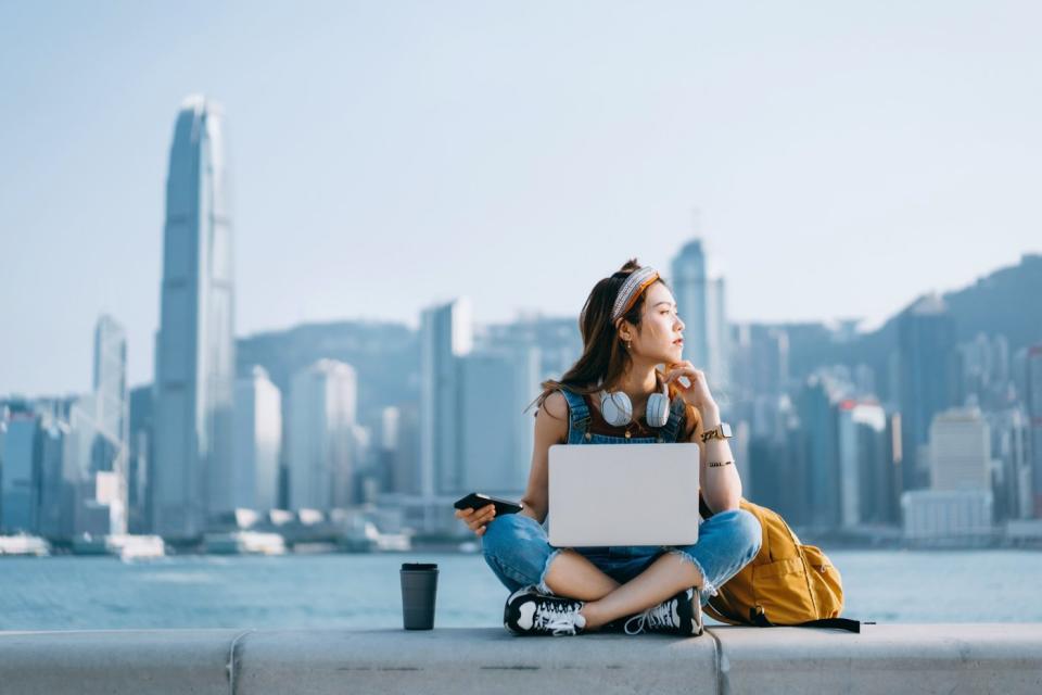 A person using a laptop at Victoria Harbor in Hong Kong.