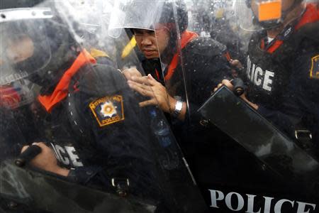 A policeman reacts as his group is cornered by anti-government protesters pushing against a barricade near the Government house in Bangkok November 25, 2013. REUTERS/Damir Sagolj