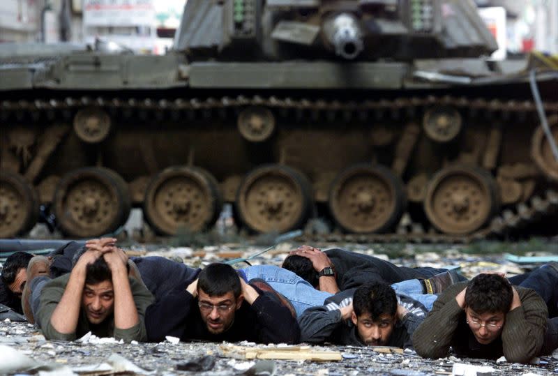 FILE PHOTO: Palestinians lie on the ground in front of an Israeli tank after they were arrested during the Israel