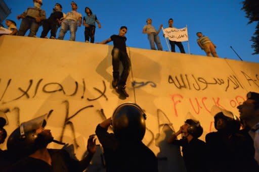 Egyptian riot police stand guard as protesters climb down from the wall of the US embassy in Cairo. Thousands of Egyptian demonstrators tore down the Stars and Stripes at the US embassy in Cairo on Tuesday and replaced it with an Islamic flag on the anniversary of the September 11, 2001 attacks in the United States, an AFP photographer reported