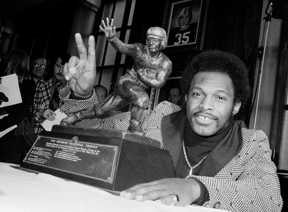 FILE - In this Dec. 2, 1975 file photo, Ohio State's running back Archie Griffin smiles and holds up two fingers as he poses with the 1975 Heisman Trophy in New York City. Griffin also won the Heisman in 1974. Griffin, the only two-time winner of the Heisman Trophy, says he'd welcome being joined in that elite company by Florida's Tim Tebow or Oklahoma's Sam Bradford. Tebow won the award two years ago as a sophomore and is quarterbacking the nation's No. 1-ranked team. Bradford, who won the Heisman last December as a sophomore, returned as quarterback for the Sooners, who are ranked No. 3. (AP Photo)