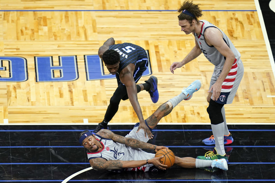 Washington Wizards guard Bradley Beal (3) looks to pass the ball as Orlando Magic center Mo Bamba (5) defends and Wizards center Robin Lopez, right, watches during the second half of an NBA basketball game, Wednesday, April 7, 2021, in Orlando, Fla. (AP Photo/John Raoux)