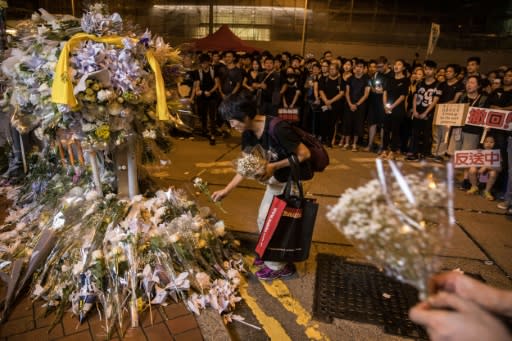 Demonstrators queued to leave flowers and tributes at the site where a protester died after falling from a building where he had been holding an hours-long anti-extradition protest