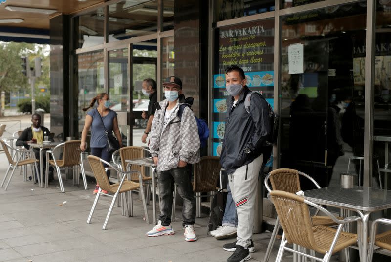 Varias personas con mascarillas en el exterior de un restaruante en el barrio de Usera de Madrid