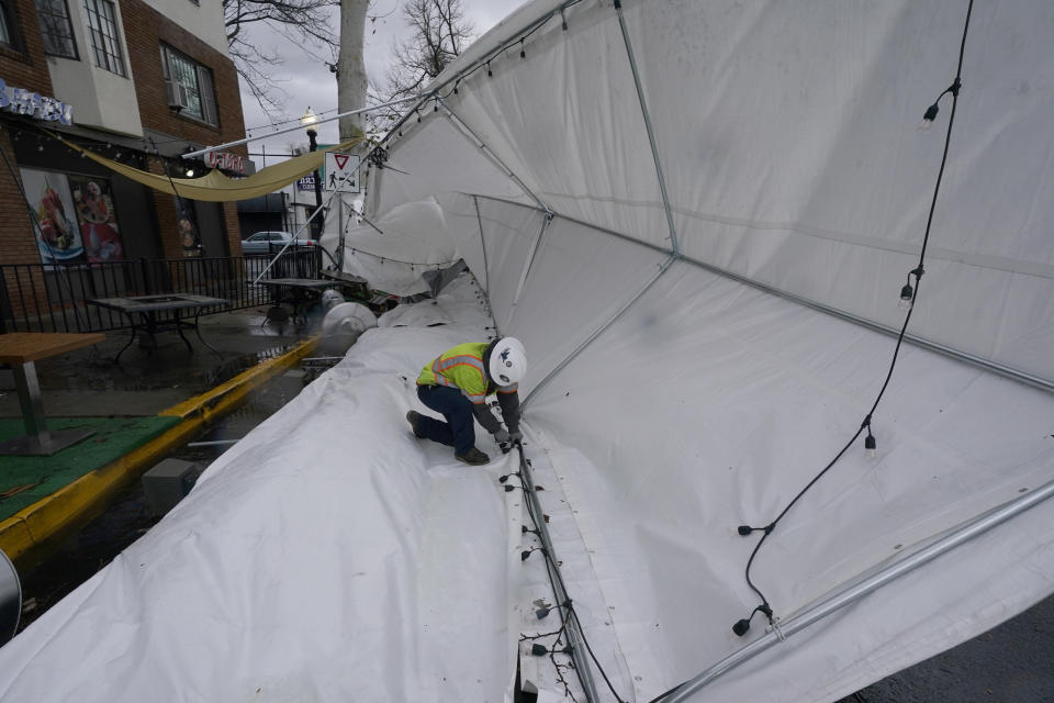 Sacramento City worker Lorenzo Montoya untie straps holding a tent that was blown over into the street by an overnight storm that swept through Sacramento, Calif., Wednesday, Jan. 27, 2021. (AP Photo/Rich Pedroncelli)