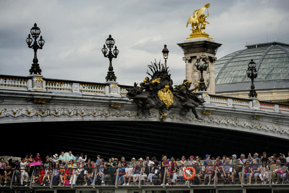 Tourists on a boat sail the Seine River in Paris, France, Tuesday, July 4, 2023. Crowds are packing the Colosseum, the Louvre, the Acropolis and other major attractions as tourism exceeds 2019 records in some of Europe’s most popular destinations. While European tourists helped the industry on the road to recovery last year, the upswing this summer is led largely by Americans, who are lifted by a strong dollar and in some cases pandemic savings. (AP Photo/Christophe Ena)