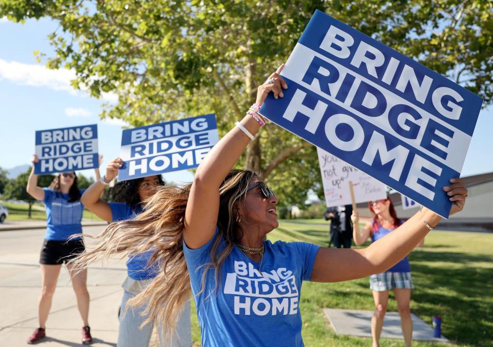 Tia Stokes dances as she holds a “Bring Ridge Home” sign and waits on 500 South for President Joe Biden’s motorcade to pass on the way to the George E. Wahlen Department of Veterans Affairs Medical Center, where he will deliver remarks, in Salt Lake City on Thursday, Aug. 10, 2023. Stokes is Ridge Alkonis’ cousin. | Kristin Murphy, Deseret News