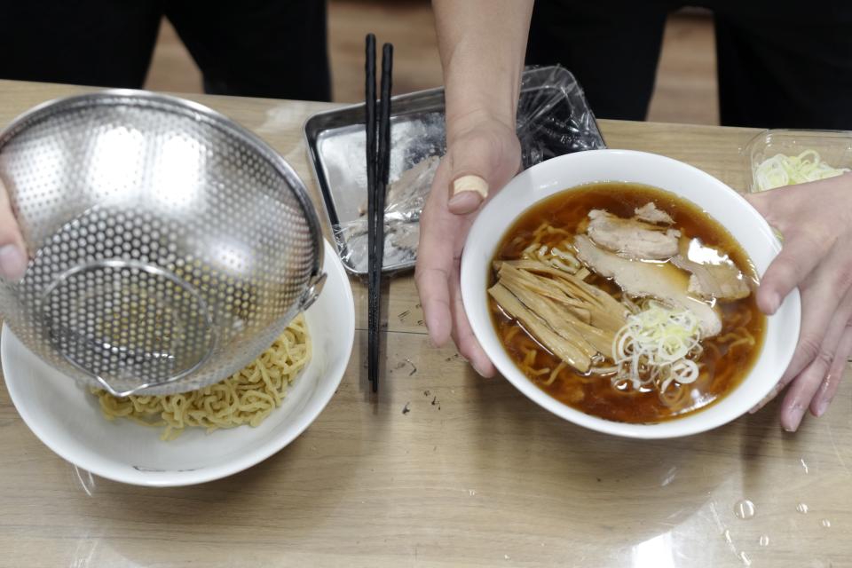 A staff member cooks one of their ramen merchandise sold online at Gourmet Innovation, in Tokyo Wednesday, April 10, 2024. Gourmet Innovation has signed on 250 of the country's top ramen joints to sell packaged versions of their soup, noodles and toppings, to be heated up in boiling water and served at home. (AP Photo/Eugene Hoshiko)