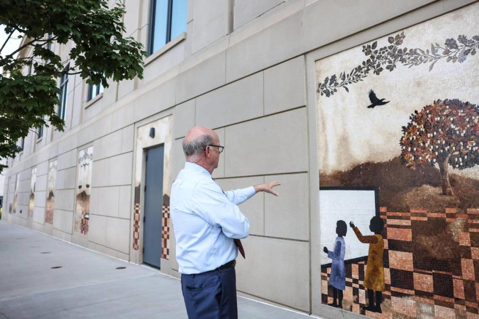 Senior U.S. District Judge Bob Conrad points to mosaics on the side of the Jonas Federal Courthouse. The art represents significant events that happen in the courthouse, he said.