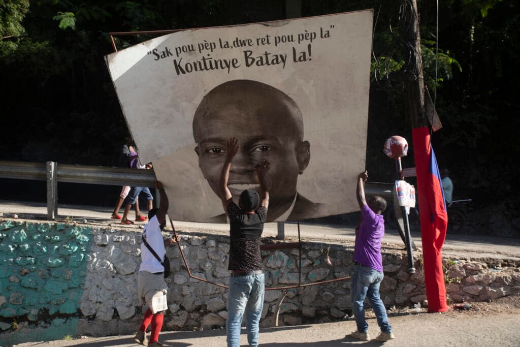 Supporters of slain Haitian President Jovenel Moise place a sign of him that reads “The purse of the people must remain with the people. Continue the fight” on Thursday, July 7, 2022 in the Petion-ville area of Port-au-Prince, Haiti. A year has passed since Moise was assassinated at his home. (AP Photo/Odelyn Joseph)