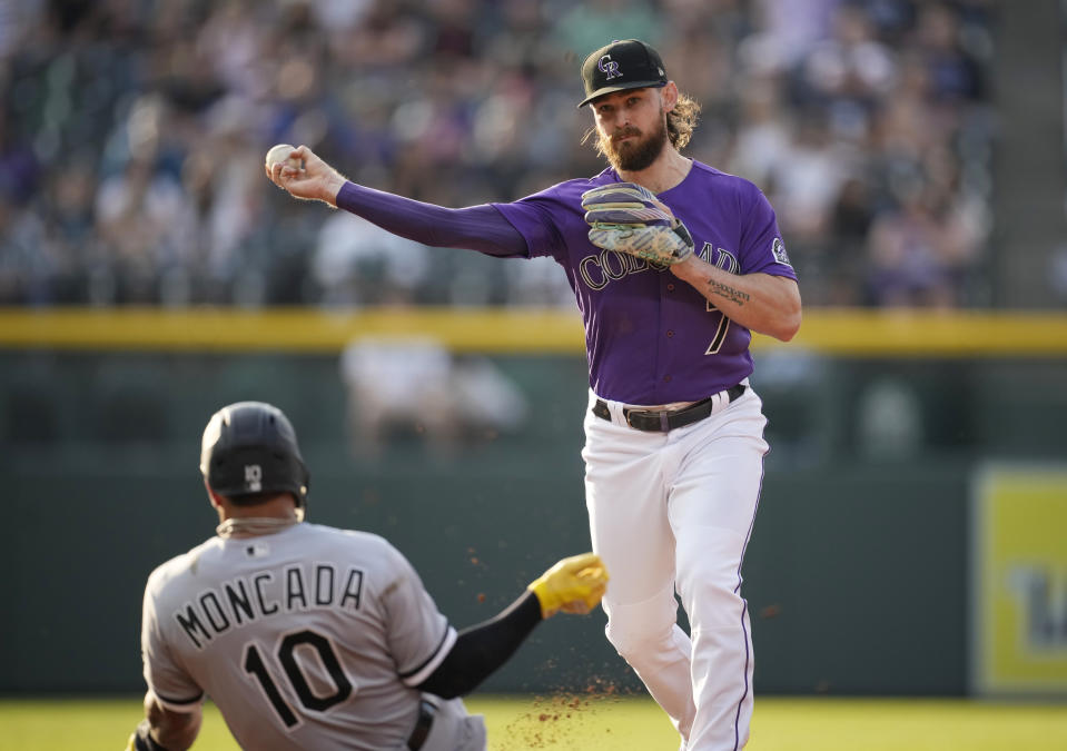 Colorado Rockies second baseman Brendan Rodgers, right, throws over Chicago White Sox's Yoan Moncada after forcing him out at second base on the front end of a double play hit into by Andrew Vaughn in the first inning of a baseball game Tuesday, July 26, 2022, in Denver. (AP Photo/David Zalubowski)