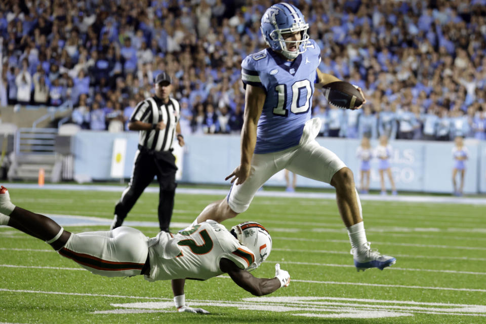 North Carolina quarterback Drake Maye (10) tries to evade a tackle attempt by Miami defensive back Jaden Davis (22) during the first half of an NCAA college football game Saturday, Oct. 14, 2023, in Chapel Hill, N.C. (AP Photo/Chris Seward)