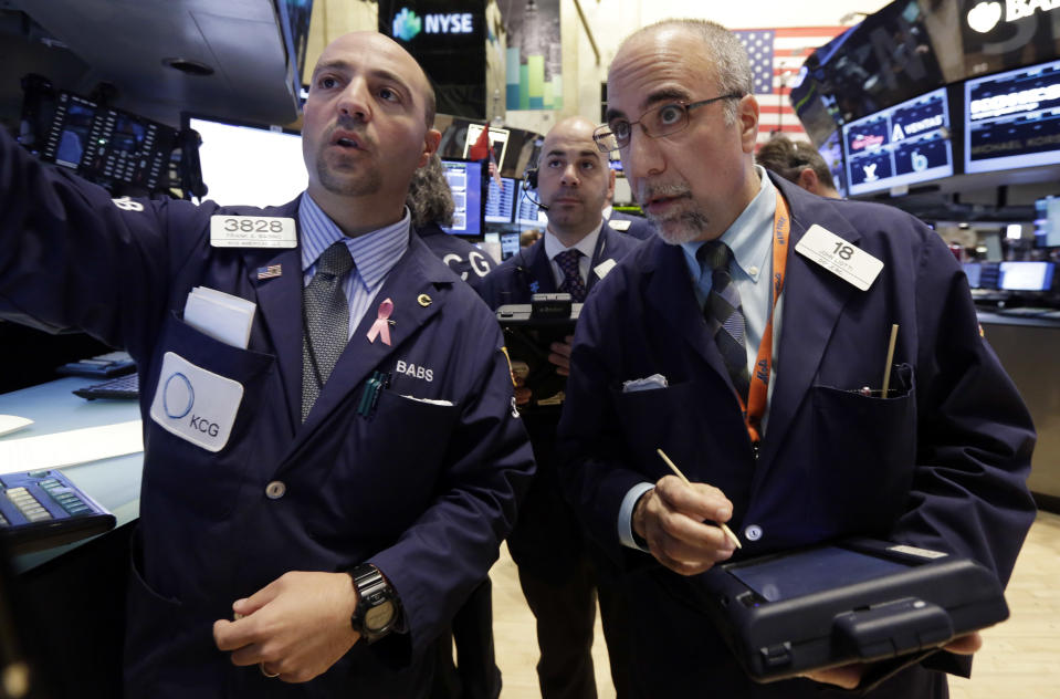Specialist Frank Babino, left, works with traders Fred DeMarco, center, and John Liotti on the floor of the New York Stock Exchange Wednesday, March 12, 2014. U.S. stocks are heading lower for the third day in a row as investors continue to worry about slower growth in China and the lingering tensions in Ukraine. (AP Photo/Richard Drew)