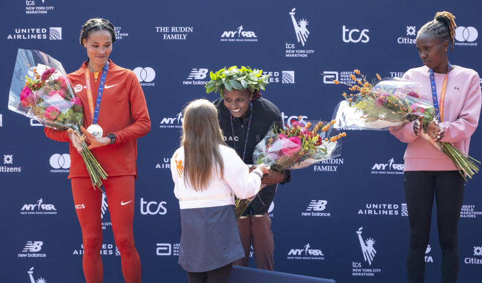 From left, second place finisher Letesenbet Gidey, of Ethiopia, first place finisher Hellen Obiri, of Kenya, and third place finisher Sharon Lokedi, of Kenya, stand with their medals and other prizes after finishing the open professional women's division of the New York City Marathon, Sunday, Nov. 5, 2023, in New York. (AP Photo/Craig Ruttle)