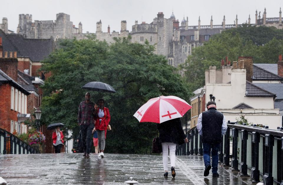 Pedestrians carry umbrellas as they cross the Windsor and Eton bridge in Berkshire in the rain (PA)