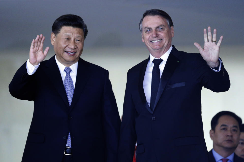 China's President Xi Jinping, left, and Brazil's President Jair Bolsonaro wave to reporters upon Xi Jinping's arrival for a bilateral meeting on the sidelines of the 11th edition of the BRICS Summit, at the Itamaraty Palace, in Brasília, Brazil, Wednesday, Nov. 13, 2019. (AP Photo/Eraldo Peres)
