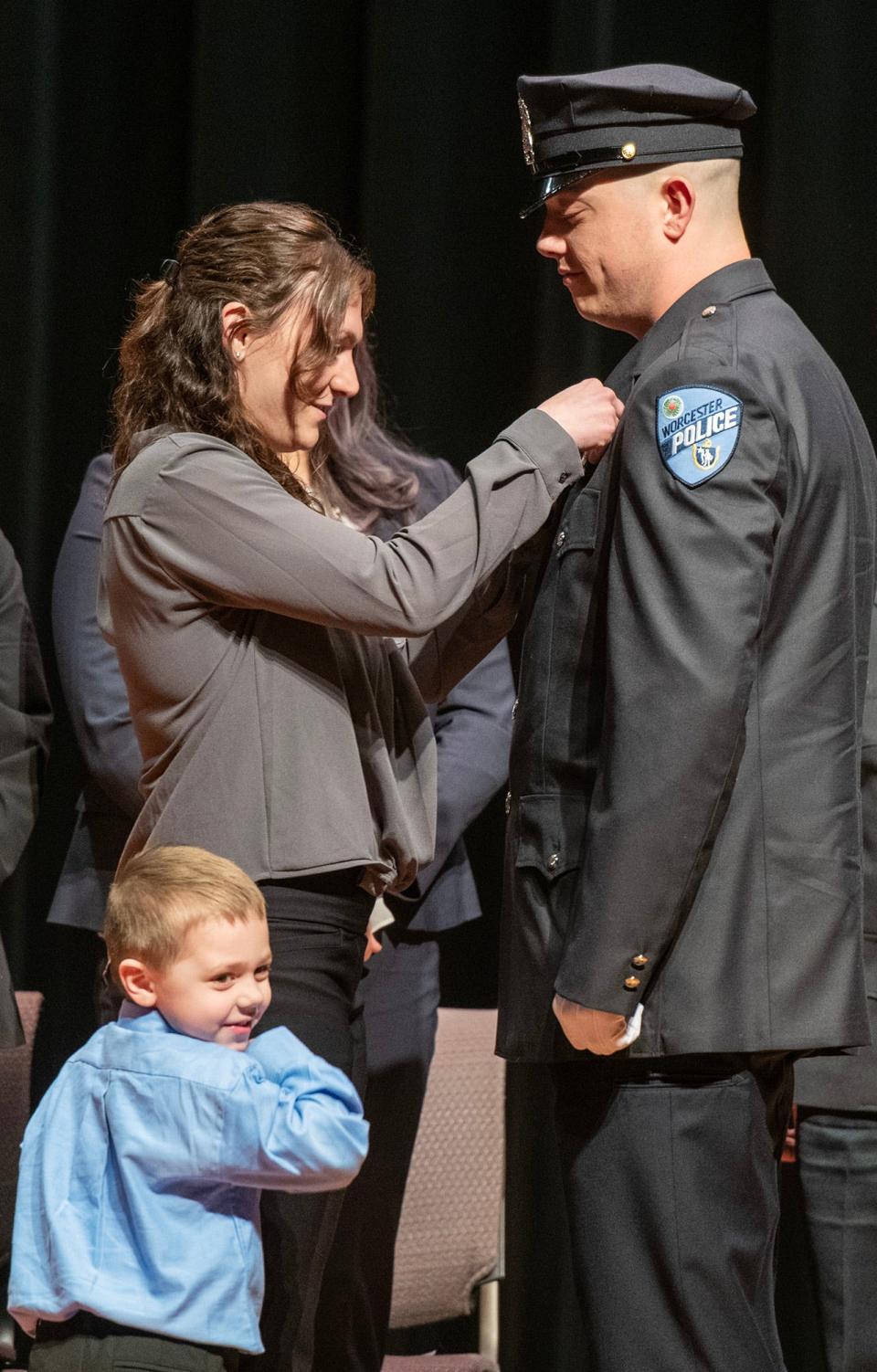 New Worcester Police Officer Timothy W. Cullen has his badge pinned on by his wife, Taylor Cullen, with their son, Timothy Jr., during police academy graduation Friday at Worcester Technical High School.