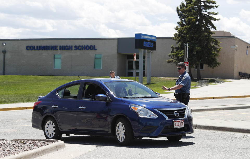 Officers from Jefferson County, Colo., Schools tell a motorist that they can not be on the property of Columbine High School, Thursday, June 13, 2019, in Littleton, Colo. The school district is considering the demolition of Columbine, the scene of a mass assault more than 20 years ago, and rebuilding the current school. (AP Photo/David Zalubowski)