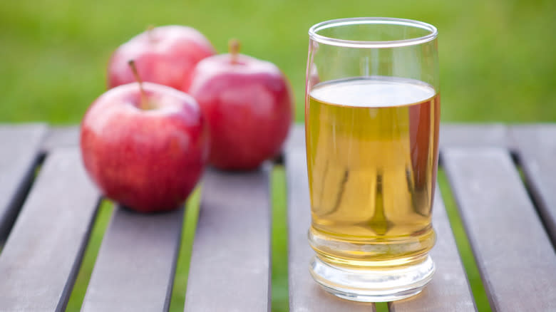 glass of apple juice on table with apples