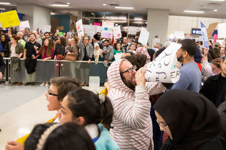 A man leads a protest chant with a makeshift megaphone during a protest against the travel ban imposed by U.S. President Donald Trump's executive order, at Dallas/Fort Worth International Airport in Dallas, Texas, U.S. January 28, 2017. REUTERS/Laura Buckman