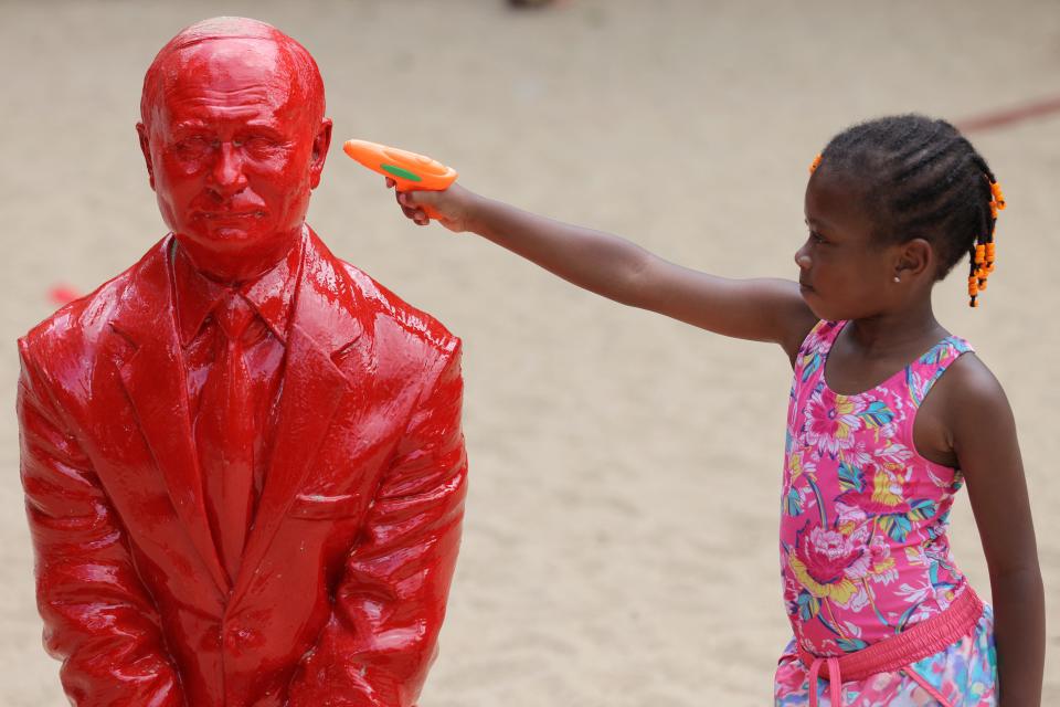 A child points a water pistol at a statue of Russian President Vladimir Putin riding a tank created by French artist James Colomina in Central Park in Manhattan, New York City, U.S., August 2, 2022.