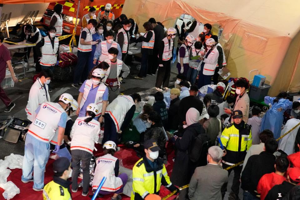 Rescue workers treat injured people on the street near the scene in Seoul (AP)
