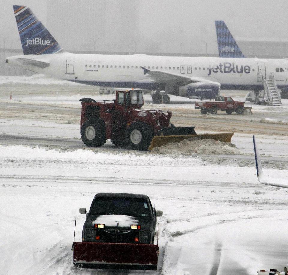 Snowplows move snow off taxiways at Newark Liberty International Airport, Monday, Feb. 3, 2014, in Newark, N.J. Another round of winter weather followed a day of unseasonable temperatures with several inches of snow in the eastern United States on Monday, closing schools, disrupting air traffic and snarling travel plans for people trying to return home from the Super Bowl in the New York area. (AP Photo/Mike Stewart)