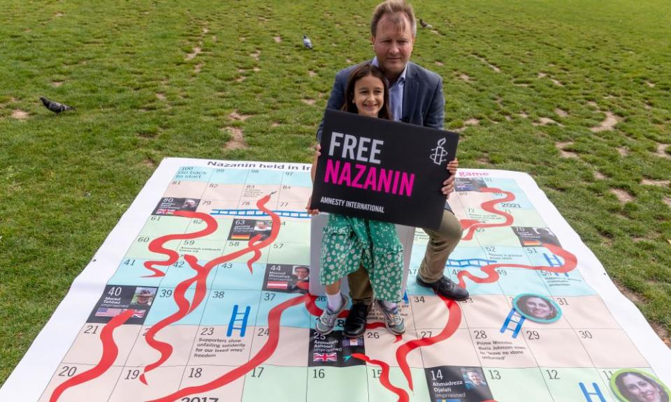 Richard and Gabriella Ratcliffe pose on a giant snakes-and-ladders board with a banner for Nazanin Zaghari-Ratcliffe who is detained in Iran.