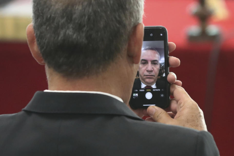 Peru's leading candidate for mayor of Lima, Daniel Urresti, looks at himself in his cellphone before start of his trial in Lima, Peru, Thursday, Oct. 4, 2018. The 62-year-old ex-general is accused of killing a journalist who was murdered while covering the bloody conflict between the Peruvian state and Shining Path guerrillas more than a quarter century ago. (AP Photo/Martin Mejia)